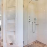 Dusche mit Duschbrause und Heizkörper an der Wand