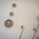 Duschkopf und Bedienelemente an der Wand