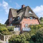 Rotes Backsteinhaus mit Strohdach und weißem Geländer