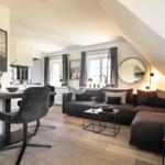 Wohnbereich mit Sofa, Esstisch und Schlafbereich unter Dachschräge.