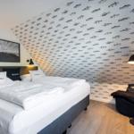 Schlafzimmer mit Bett, Fischmotivwand und Stehlampe.