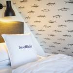 Schlafzimmer mit Fischmotiv-Wand und Kissen mit Aufdruck.