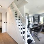 Haus mit Treppe, Essbereich und Wohnzimmer. Toilette im Hintergrund.