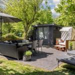 Terrasse mit Sitzgruppe, Sonnenschirm und Liegestühlen um einen Gartenhaus.