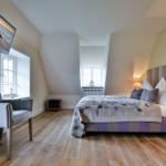 Schlafzimmer mit Bett, TV und Holzboden.
