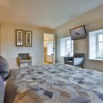 Schlafzimmer mit Bett, Fenstern und Fernseher an der Wand.