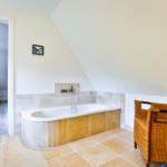 Bad mit Badewanne, Wickerstuhl und Blick in Schlafzimmer