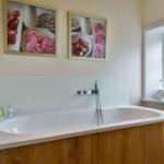 Bad mit Whirlpool, Wandbildern und Fenster mit Handtuch.