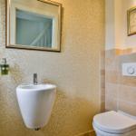 Badezimmer mit Toilette, Waschbecken und Spiegel an der Wand.
