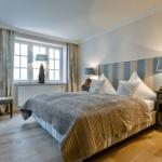 Schlafzimmer mit Bett, Nachttischen und Fenster mit Vorhängen.