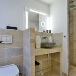 Badezimmer mit Dusche, Waschbecken und Toilette. Steinwand und Spiegel.