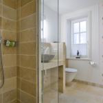Dusche mit Glaswand, Waschbecken und Toilette in moderner Badezimmerausstattung.
