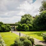 Garten mit gepflastertem Weg, grüner Rasen und Hecken. Hinterhof mit Blick auf Meer.