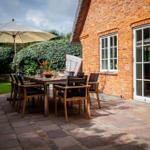 Terrasse mit Tisch, Stühlen und Sonnenschirm neben Backsteinhaus
