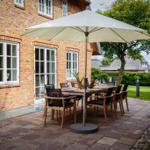 Terrasse mit Tisch, Stühlen und Sonnenschirm vor Backsteinhaus.