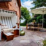 Haus mit Strandkorb und Terrasse mit Tisch, Stühlen und Sonnenschirm.