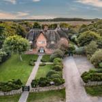 Traditionelles Fachwerkhaus mit Strohdach und gepflegtem Garten. 