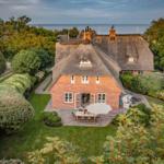 Haus mit Strohdach, Garten und Meerblick.
