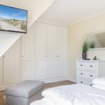 Schlafzimmer mit Bett, Kleiderschrank und Fernseher an der Wand.
