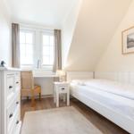 Schlafzimmer mit Doppelbett, Schreibtisch und Fenster