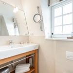 Badezimmer mit Waschbecken, Spiegel und Fenster