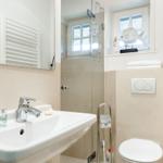 Badezimmer mit Waschbecken, Dusche und Toilette. Fenster mit Fischdekoration.