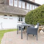 Haus mit strohgedecktem Dach und Außenbereich mit Tisch und Stühlen.