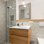 Badezimmer mit Dusche, Waschbecken und Spiegel.