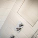 Dusche mit Chromarmaturen und weißen Fliesen