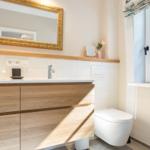 Badezimmer mit Waschtisch, Spiegel und Toilette. Fenster mit Blick auf Garten.