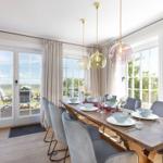 Esszimmer mit Holztisch, grauen Stühlen und großen Fenstern zur Außenterrasse.