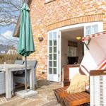 Terrasse mit Esstisch, Stühlen und Strandkorb vor Backsteinhaus