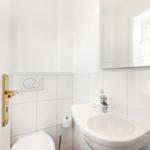 Badezimmer mit Toilette, Waschbecken und Spiegel.