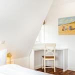 Schlafzimmer mit Schreibtisch, Bett und Wandbild