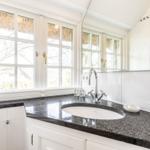 Badezimmer mit Waschbecken, Spiegel und Fenster mit Blick auf Dach