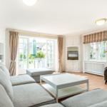 Wohnzimmer mit Sofa, Couchtisch und Fernseher. Durchgangstür zum Garten.
