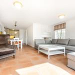 Wohn- und Essbereich mit Sofa, Sessel und Terrakottboden