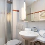 Badezimmer mit Dusche, Waschbecken und Toilette.