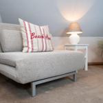 Sofa mit Kissen, Lampe und Pflanze in einem Raum mit Steigung.
