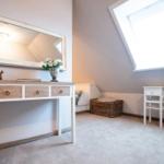 Schlafzimmer mit Dachfenster, Schreibtisch und Spiegel an der Wand.