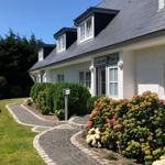 Haus mit Dachgauben, gepflastertem Weg und Blumenbeeten im Vorgarten.
