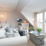 Wohnzimmer mit Sofa, Sessel und Essbereich unter Dachschräge mit Fensterblick.