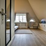 Dachgeschosszimmer mit Holzboden, Fenster und Sitzgelegenheit.