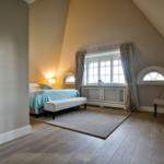 Schlafzimmer mit Dachschräge, Bett, Fenster und Sessel.