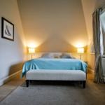 Schlafzimmer mit Bett, Nachttisch und Fenster.