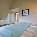 Schlafzimmer mit Bett, Kleiderschrank und Fernseher an der Wand.