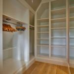 Großer Kleiderschrank mit Holzregalen und Hängern.