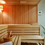 Sauna mit Holzbank, Eiche und Eimer. Pflanze und Fenster sichtbar.