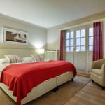 Schlafzimmer mit Doppelbett, Sessel und Fenster zur Terrasse.