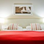 Doppelbett mit roter Decke, zwei Nachttische und Wandbild mit Segelyacht.